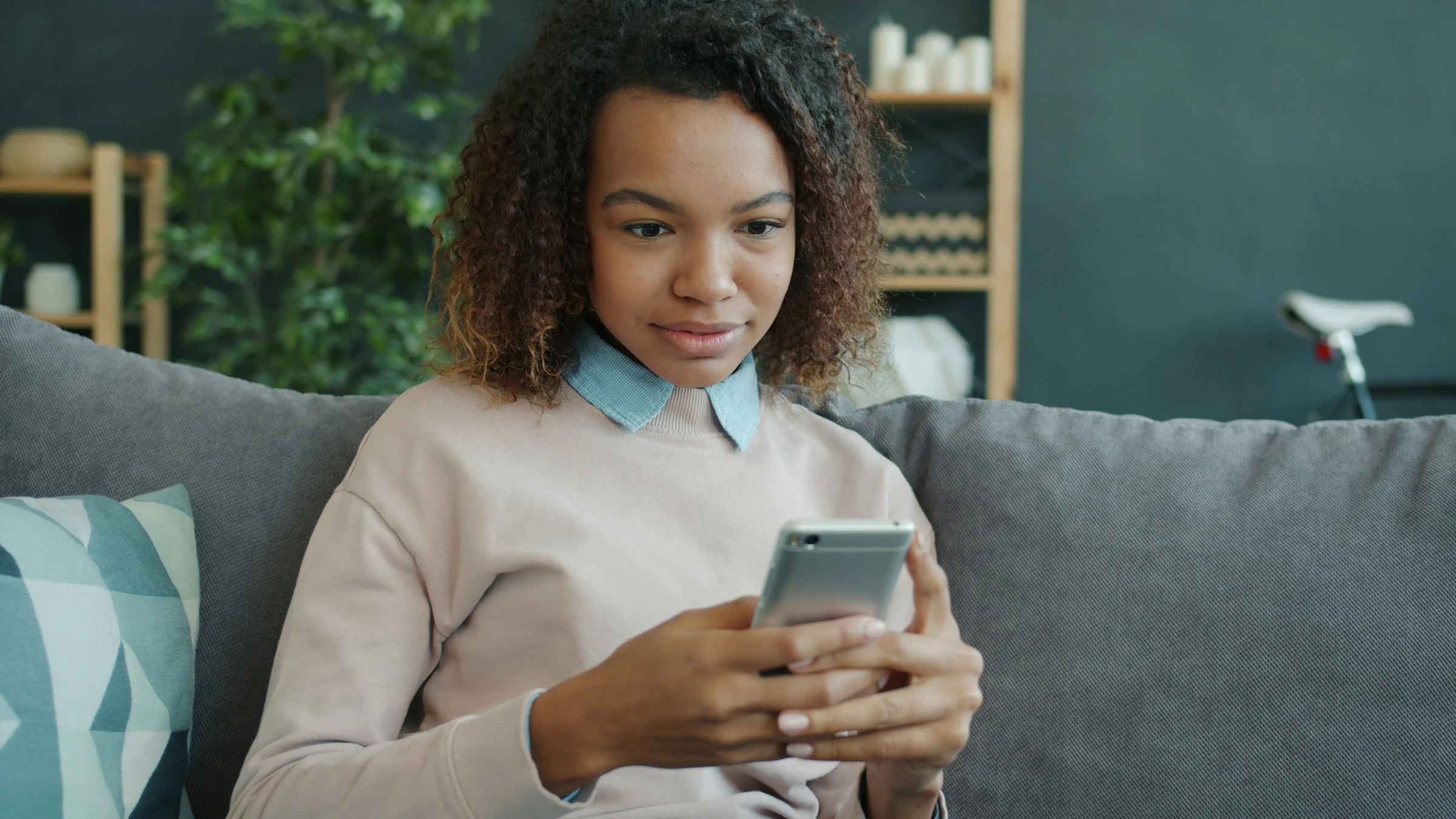 Eine Frau liest auf dem Sofa eine Nachricht auf ihrem Telefon